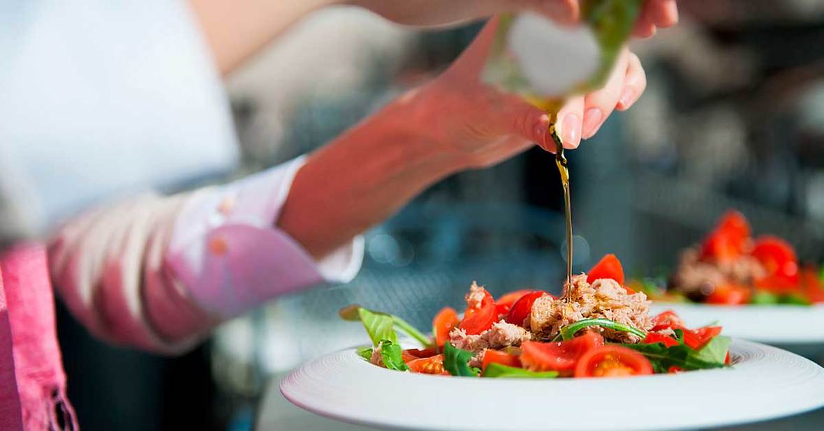 Mujer mayor que sufre de hiporexia aliñando una ensalada para aumentar sus ganas de comer