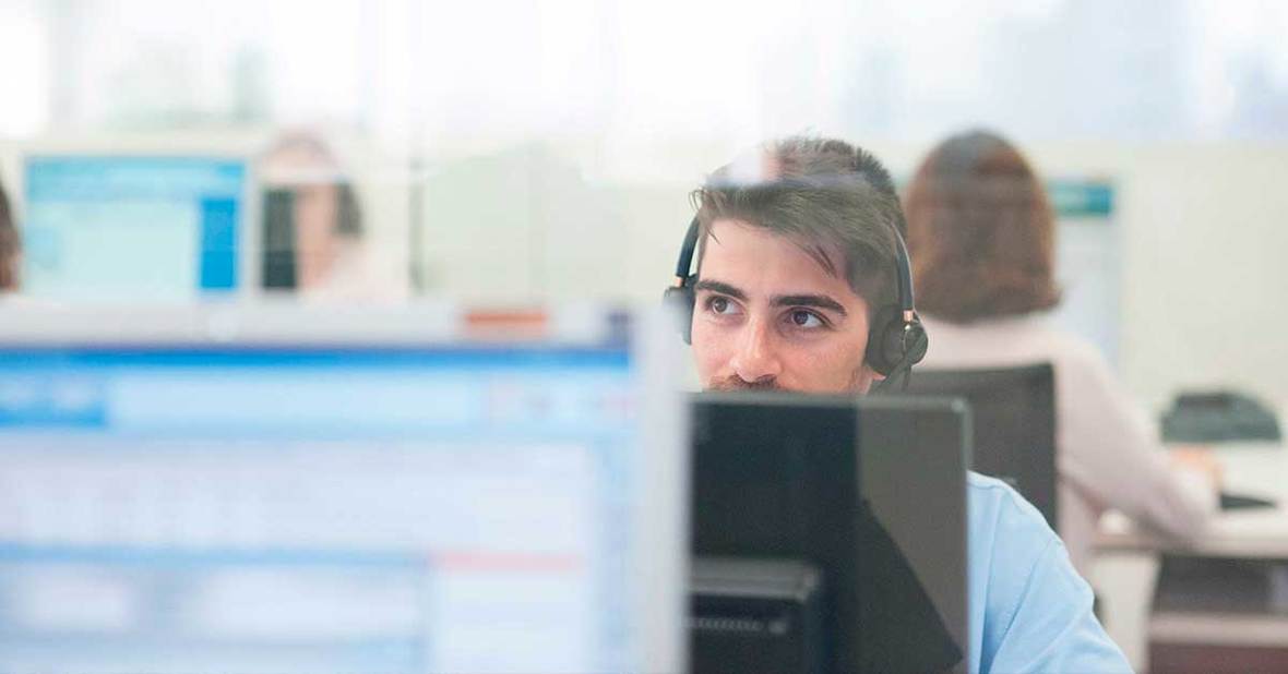 Trabajador de teleasistencia con cascos sentado en frente de un ordenador