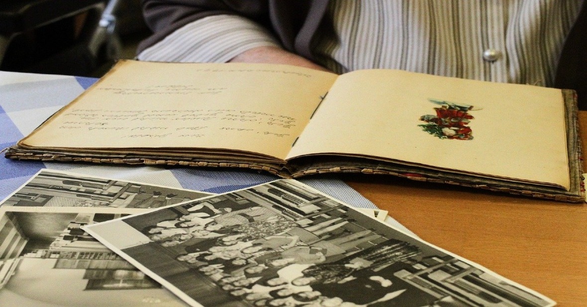 Hombre mayor mirando fotos con una libreta delante para no aburrirse en casa