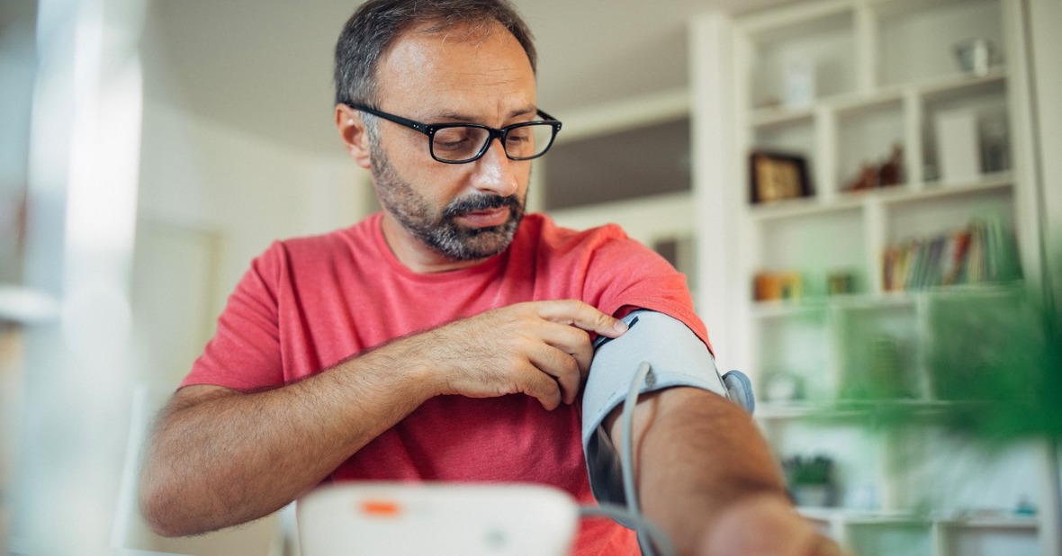 Adulto tomándose la tensión arterial con un tensiómetro en su casa