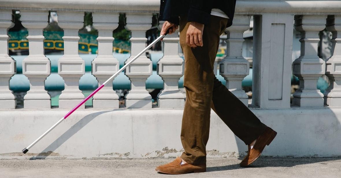 Hombre mayor que arrastra los pies caminando por la calle con bastón