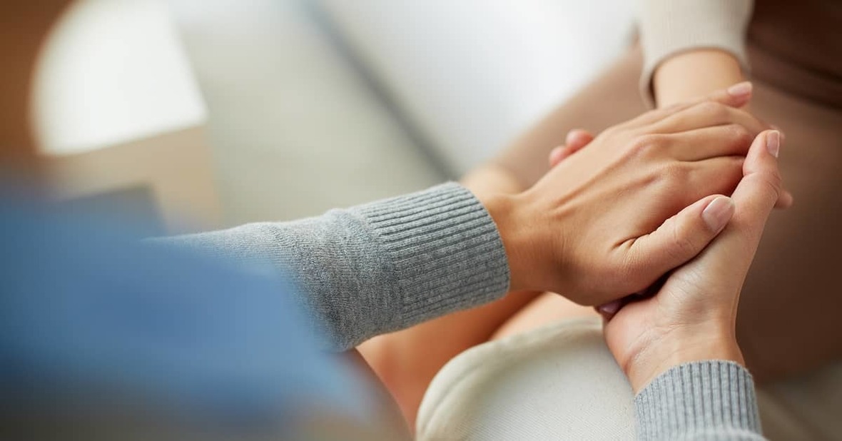 Cuidadora sosteniendo la mano de una mujer mayor