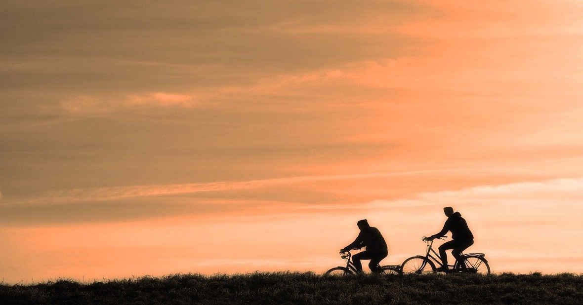 Dos personas montando en bicicleta, una actividad física recomendada para adultos mayores