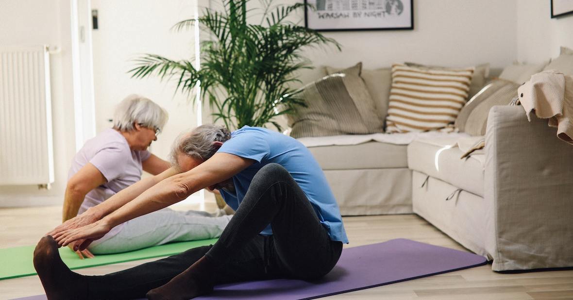 Personas mayores haciendo yoga en su salón.