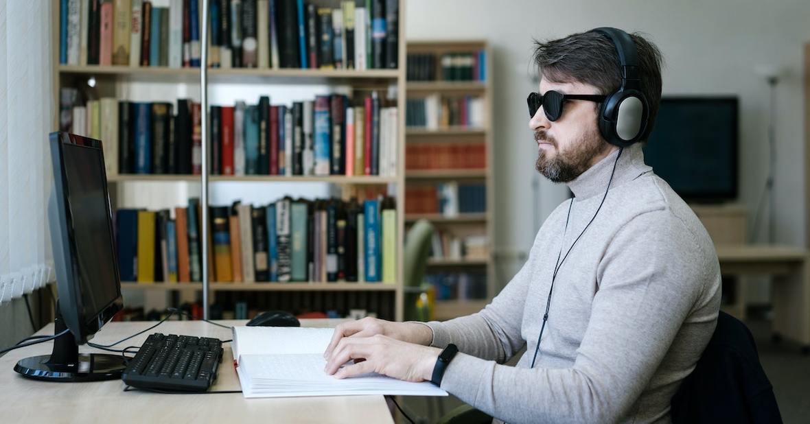 Chico ciego frente a un ordenador leyendo en braile.